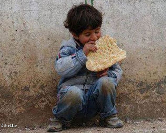 Un petit garon libanais pauvre, mange du pain qu'on lui a donn!